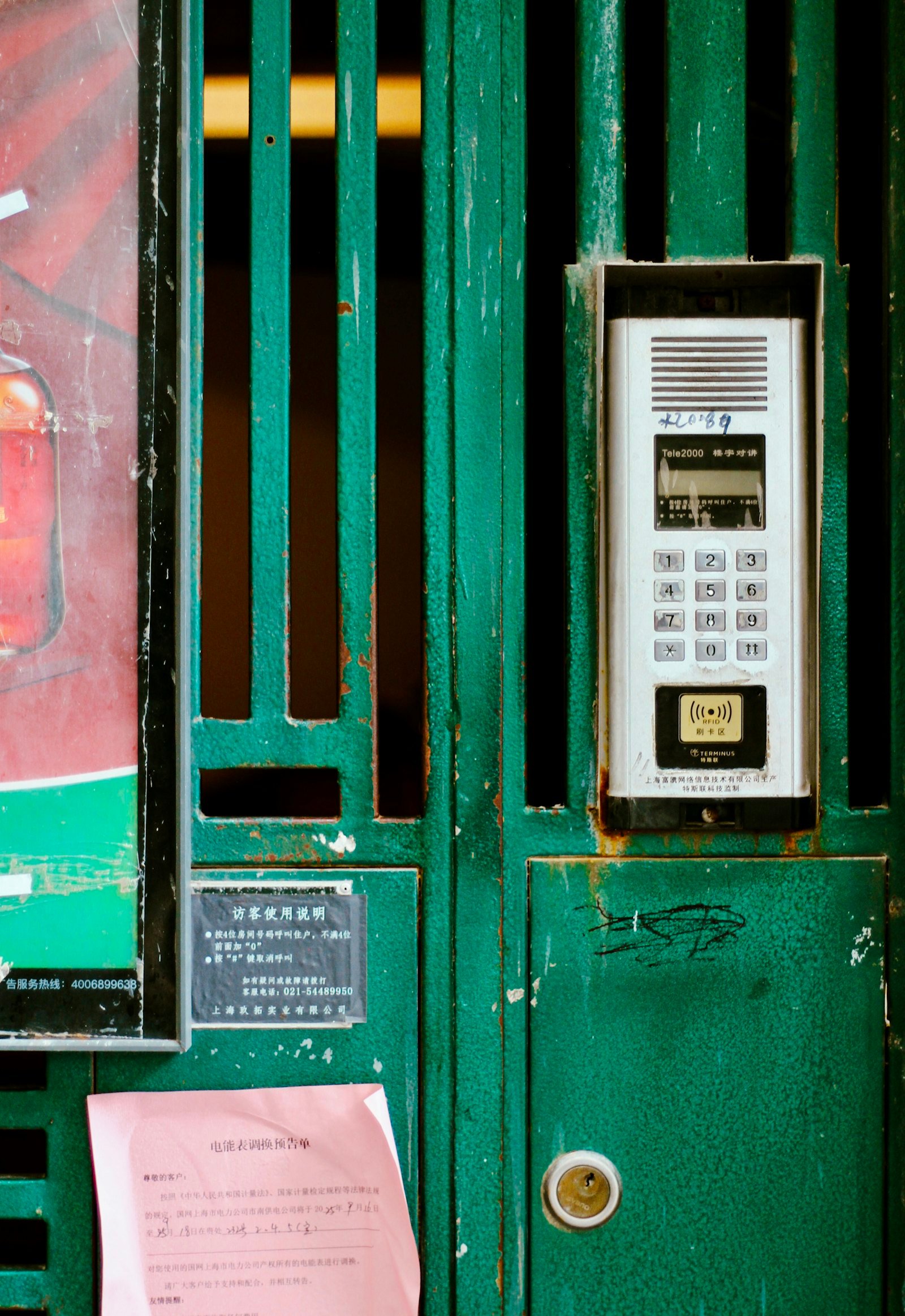 Platine d'interphone fixée sur un portail vert